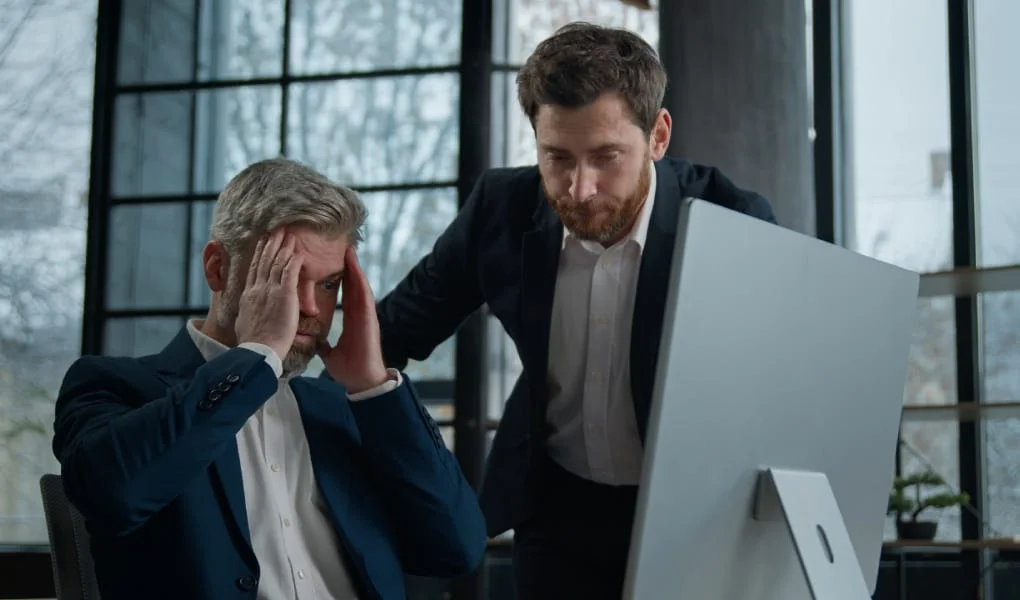 Two upset frustrated Caucasian men businessmen coworkers looking at computer screen in office receiving email reading bad news disappointment failure business problem crisis electronic error data loss